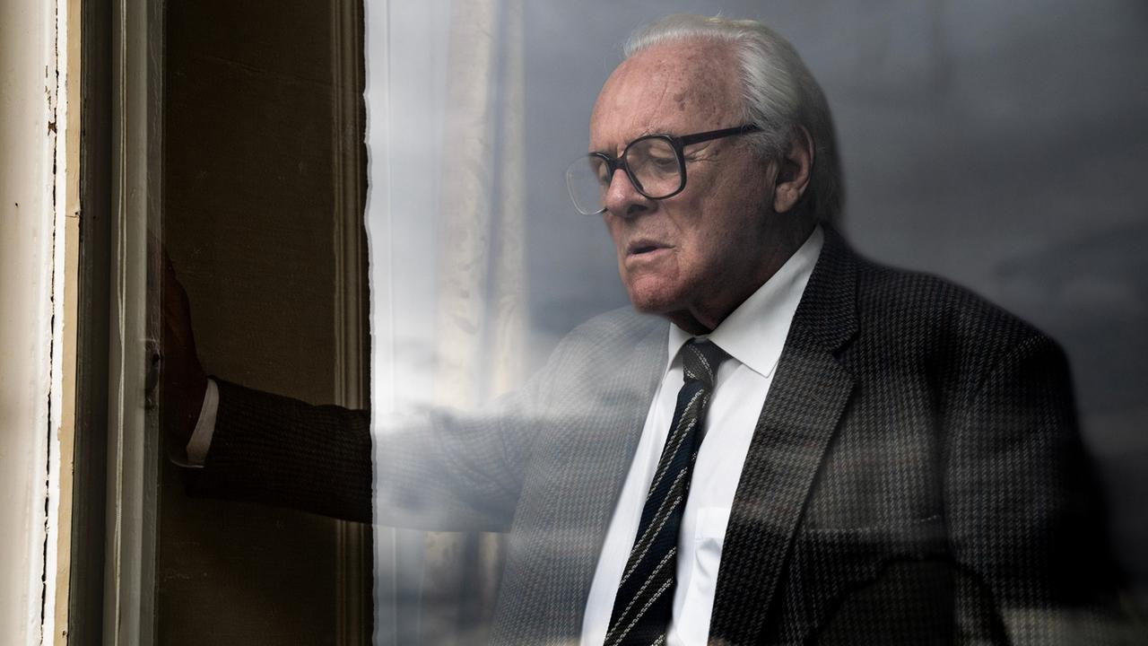 "One Life - Wer ein Leben rettet, rettet die ganze Welt": Nicholas Winton (Anthony Hopkins) steht im dunklen Anzug an einem großen Fenster.