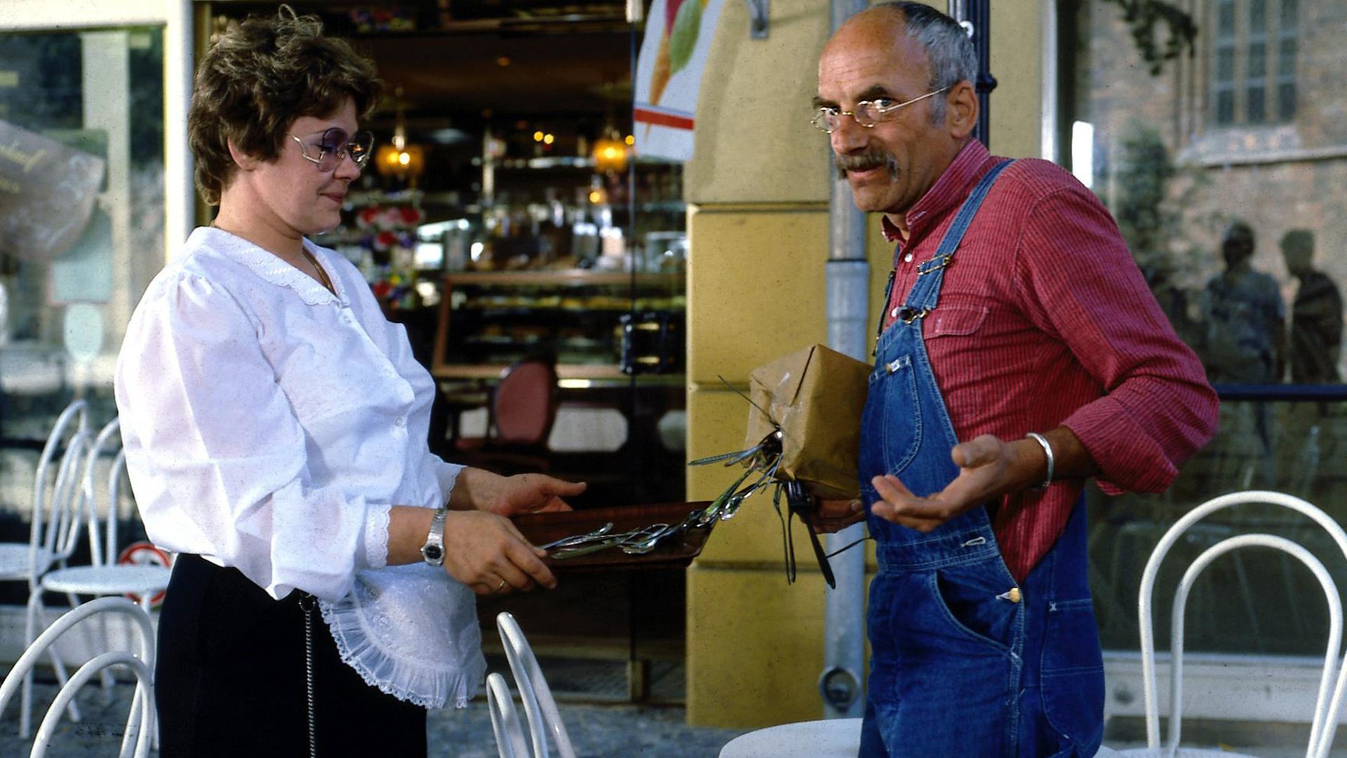 Peter Lustig steht vor einem Café. In einem Paket, das er unter dem Arm trägt, befindet sich ein starker Magnet, weshalb das Metall-Besteck aus dem Kasten der Kellnerin vor ihm davon angezogen wird und nun am Paket hängt. Peter schaut irritiert in die Kamera.