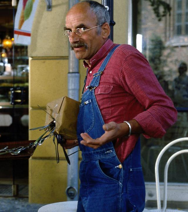 Peter Lustig steht vor einem Café. In einem Paket, das er unter dem Arm trägt, befindet sich ein starker Magnet, weshalb das Metall-Besteck aus dem Kasten der Kellnerin vor ihm davon angezogen wird und nun am Paket hängt. Peter schaut irritiert in die Kamera.