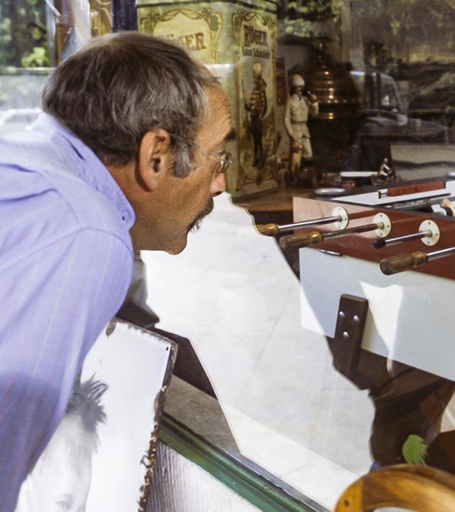 Peter schaut durch ein Schaufenster, hinter dem ein Tischkicker zu sehen ist.