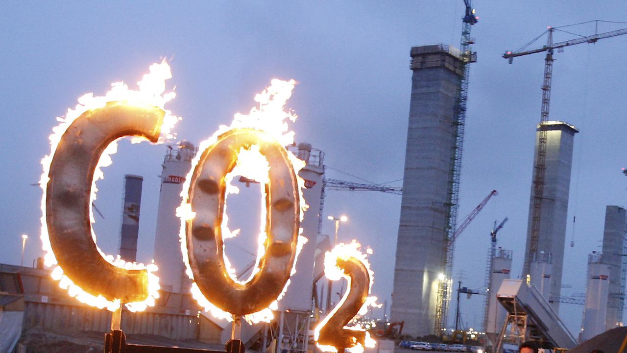 Brennendes CO2-Schild  vor Kohlekraftwerk