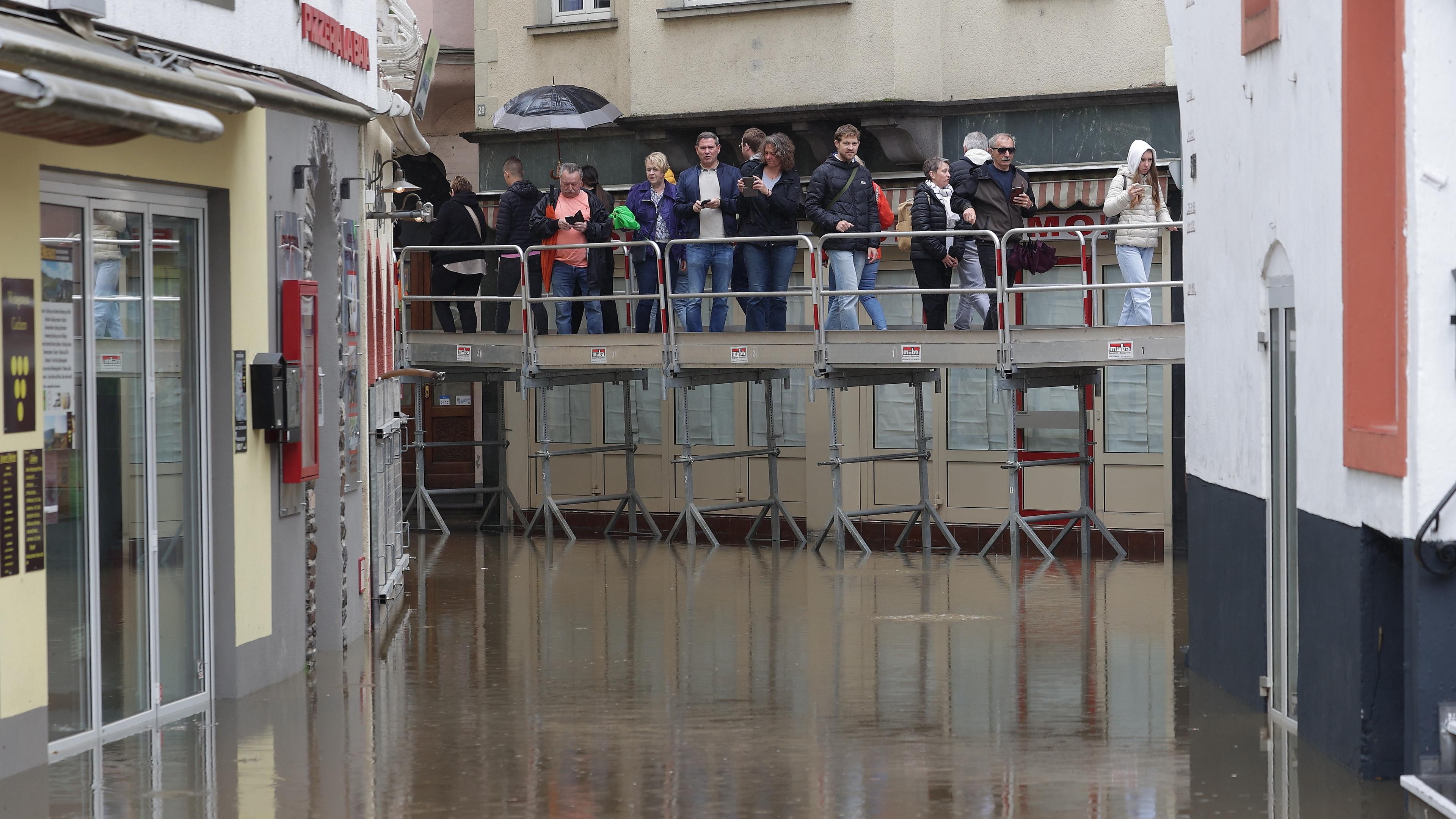 Hochwasser in Rheinland-Pfalz - Cochem. Menschen laufen über ein Baugerüst über das Wasser.