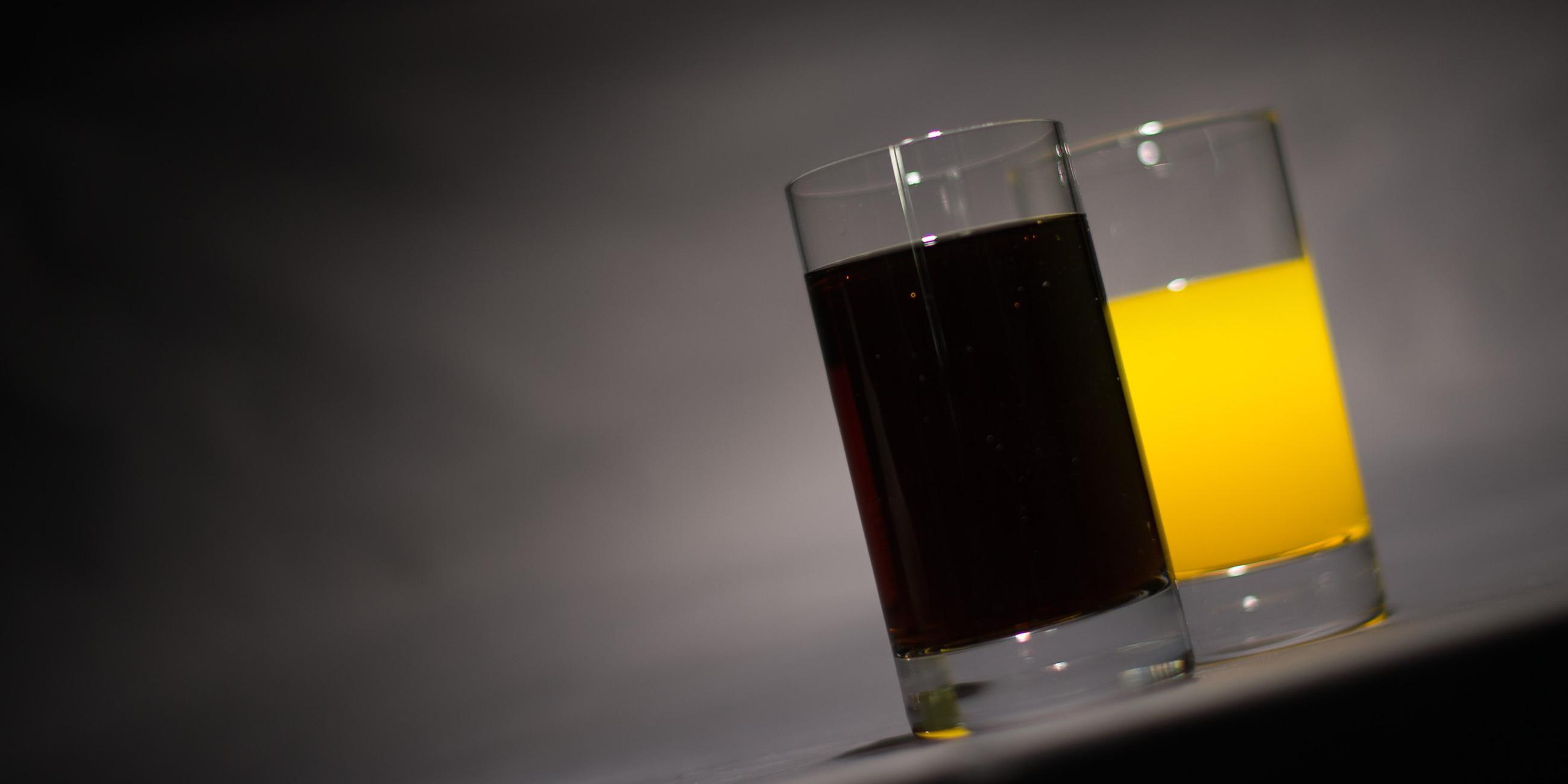Ein Glas mit Cola steht neben einem Glas mit Orangenlimonade, Archivbild