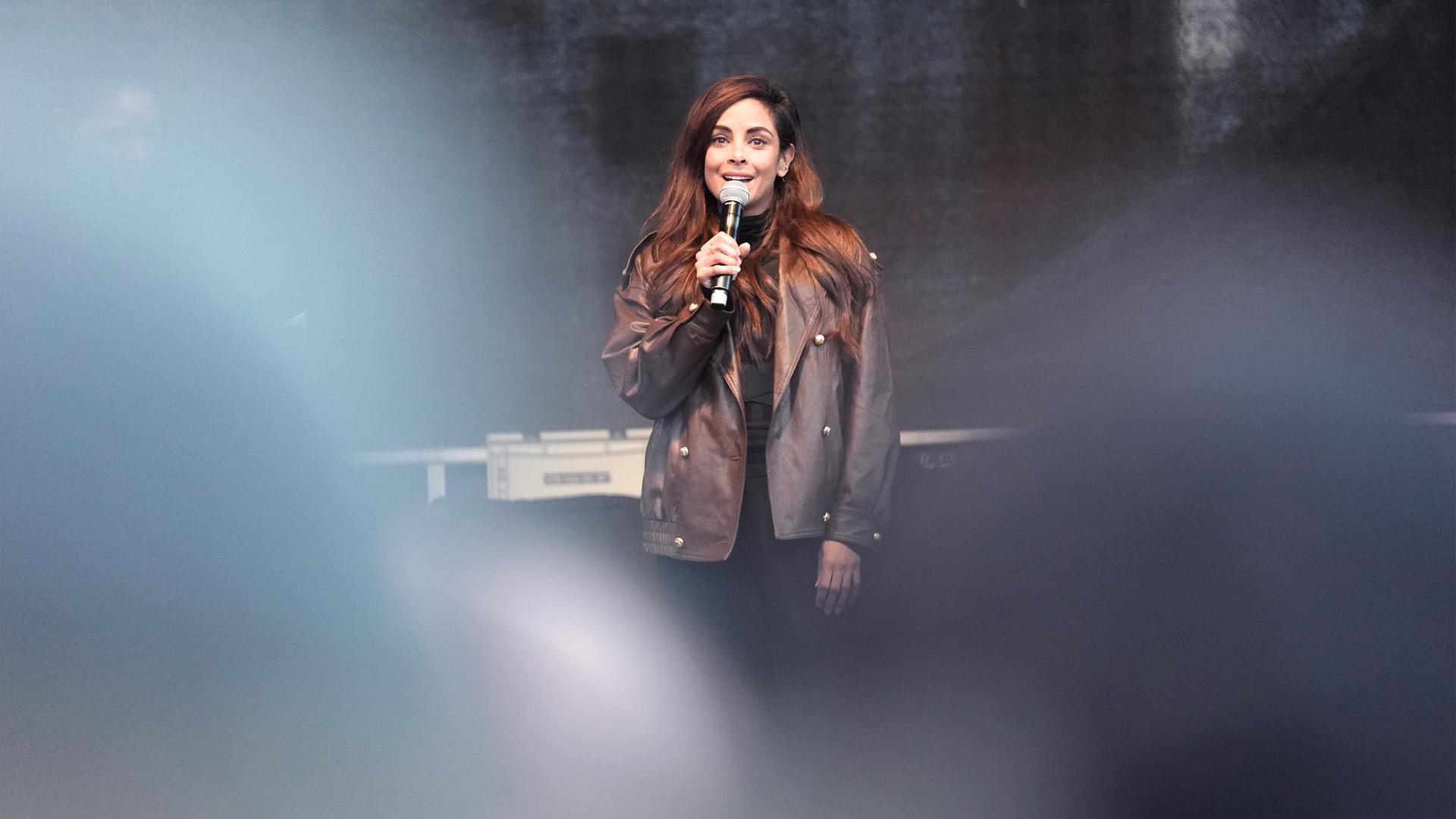 Frau spricht auf Bühne mit Mikofon in der Hand