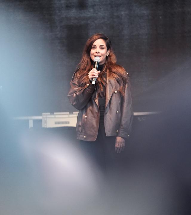 Frau spricht auf Bühne mit Mikofon in der Hand