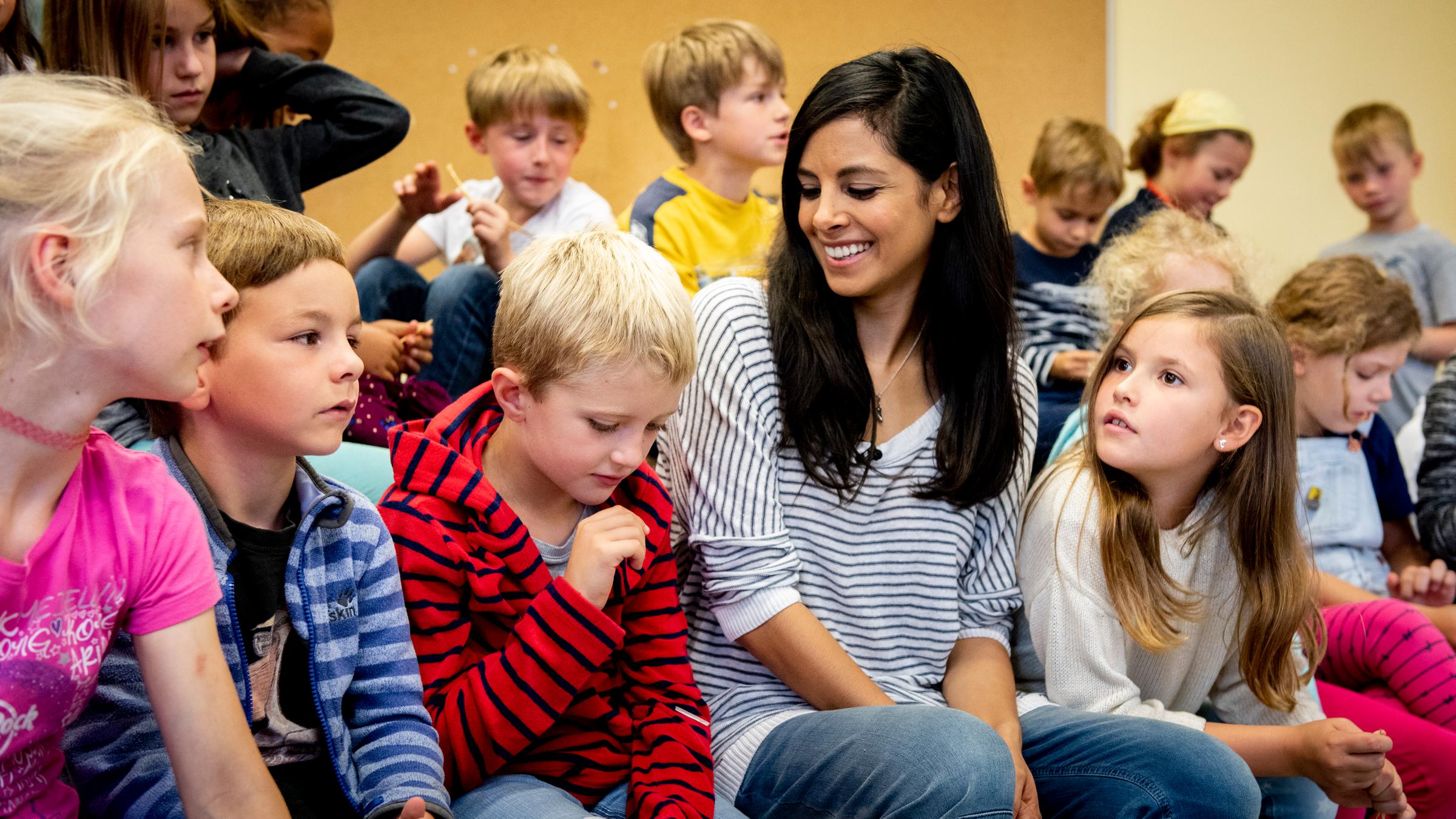  "No More Boys and Girls (2)": Collien Ulmen-Fernandes sitzt in einer Reihe mit Kindern im Grundschulalter. Sie schaut auf ein Mädchen mit langen Haaren zu ihrer Linken und lächelt.