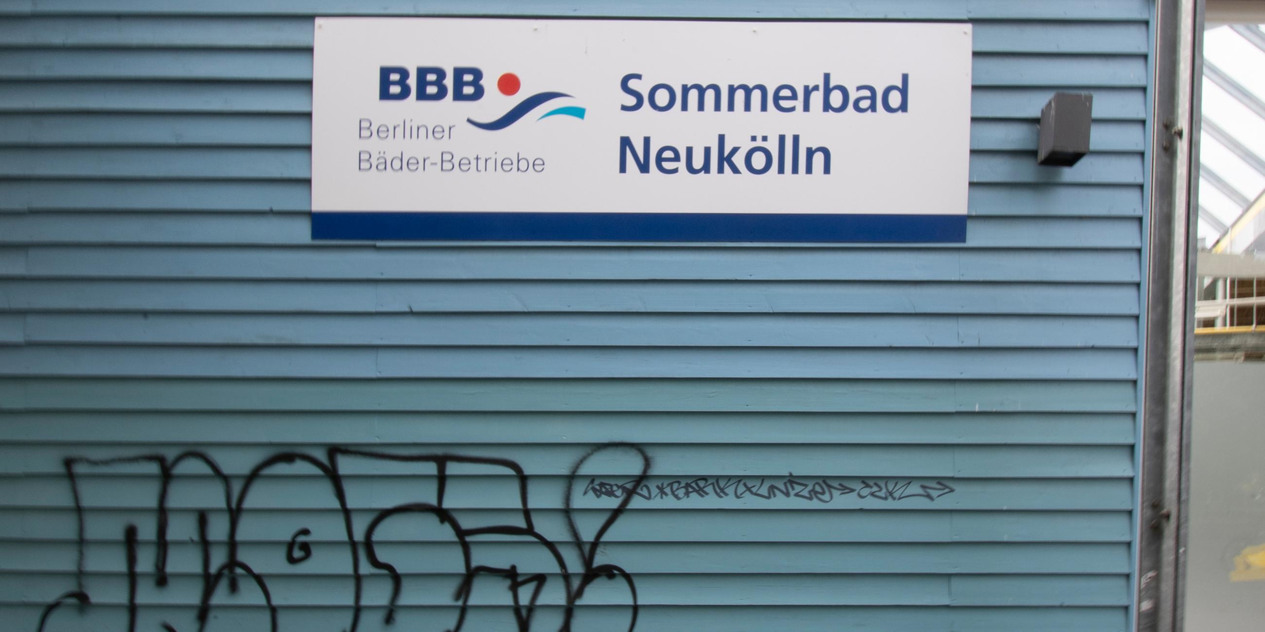 Ein Schild mit dem Logo der Berliner Bäder-Betriebe und dem Schriftzug "Sommerbad Neukölln" ist an der Fassade des Sommerbades am Columbiadamm in Neukölln zu sehen. 