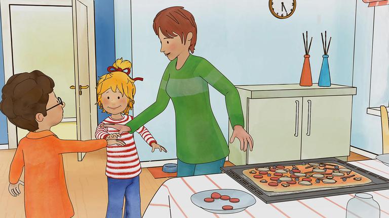 Conni, Simon und Mama beglückwünschen sich nachdem sie eine Pizza belegt haben, die auf einem Blech neben Mama auf dem Tisch liegt. Die Pizza muss nur noch in den Ofen geschoben werden. 