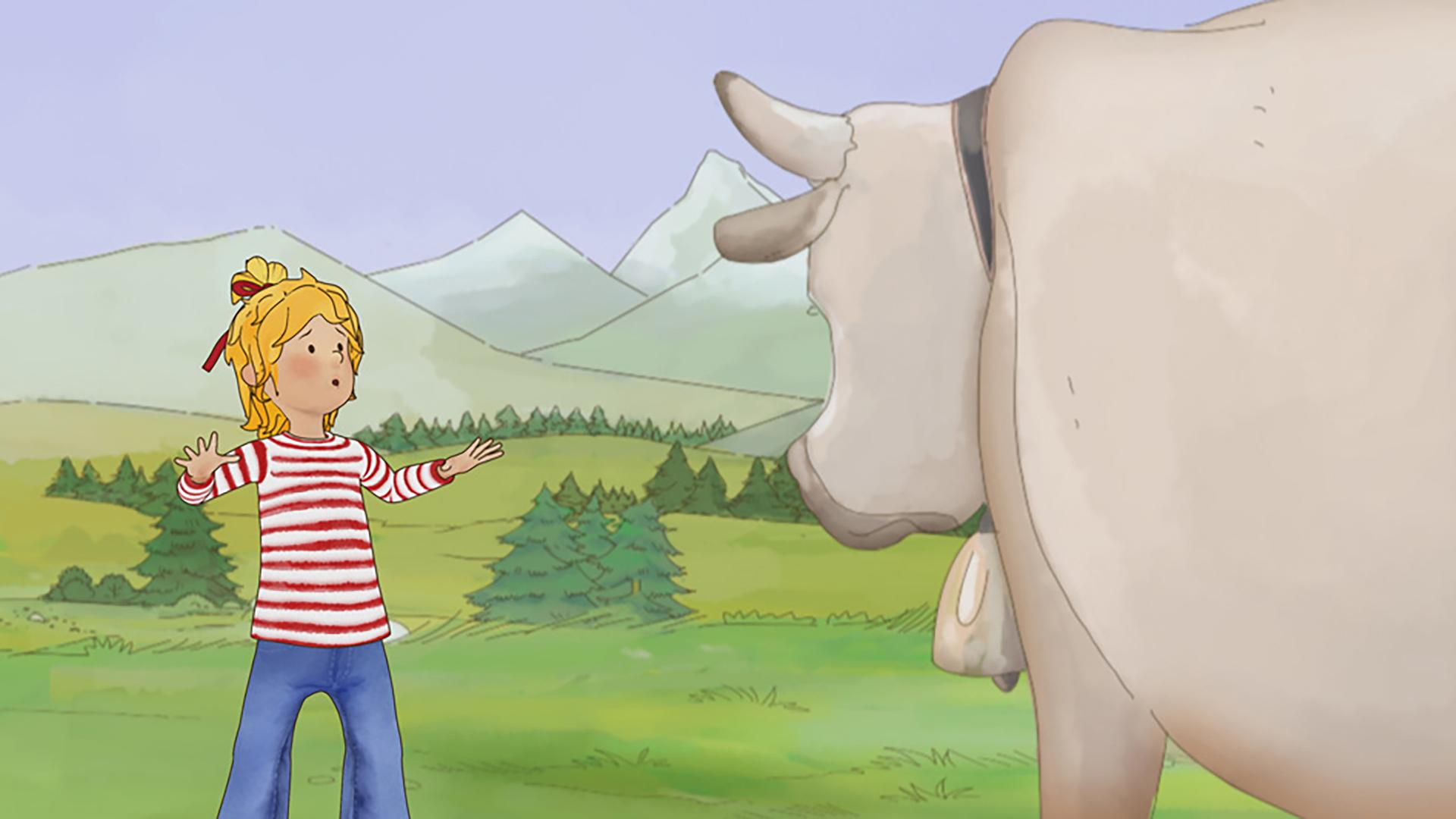 Conni erschrickt, weil sie auf eine Kuh trifft, die plötzlich vor ihr steht. Im Hintergrund ist eine Berglandschaft zu sehen.