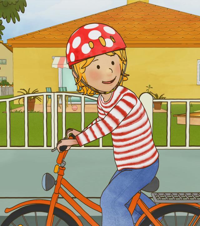 Conni sitzt mit Helm auf ihrem Fahrrad und übt den Schulterblick.