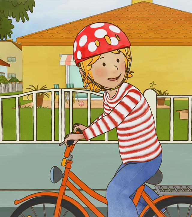 Conni sitzt mit Helm auf ihrem Fahrrad und übt den Schulterblick.