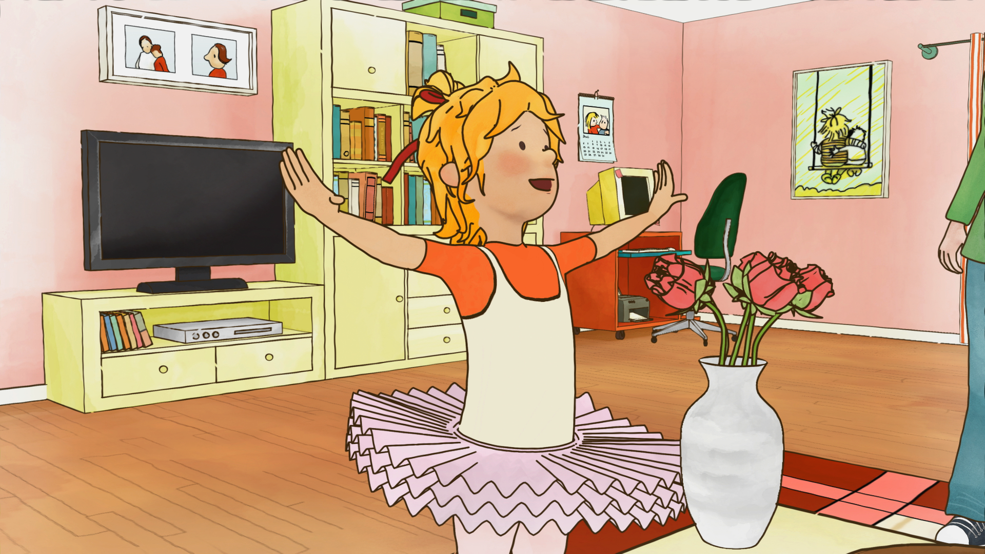 Conni tanzt im Tutu im Wohnzimmer. Sie hebt fröhlich ihre Arme in die Höhe.