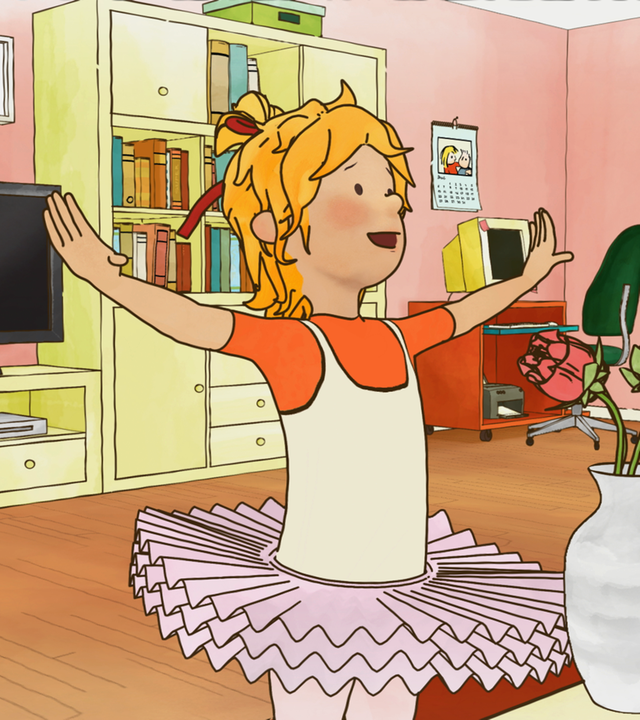 Conni tanzt im Tutu im Wohnzimmer. Sie hebt fröhlich ihre Arme in die Höhe.