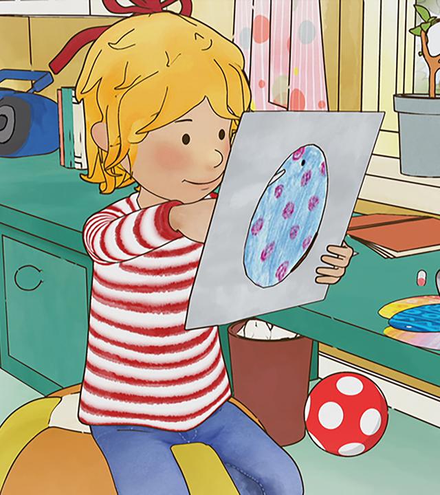 Conni bemalt Ostereier. Neben ihr sitzt eine Katze auf dem Tisch und schaut durch das Fenster nach draußen.