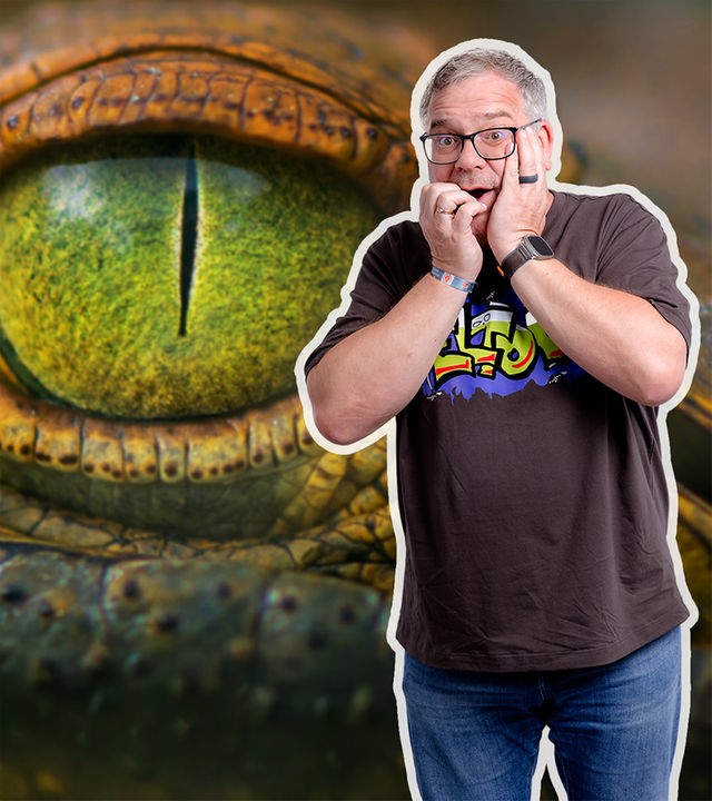Elton schaut ängstich in die Kamera. Hinter ihm ist ein übergroßes Auge eines Krokodils zu sehen. 