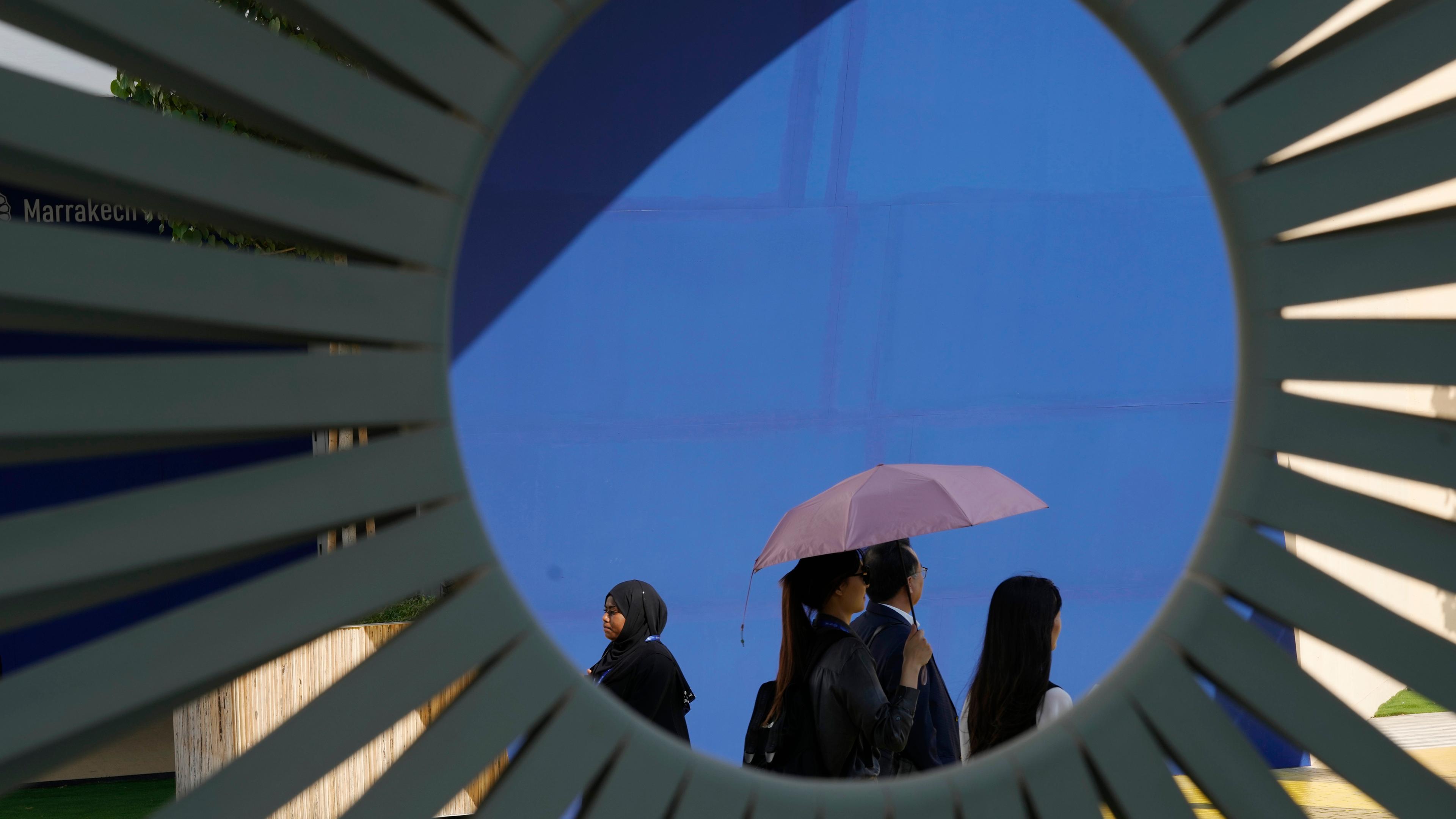 Eine Frau schützt sich mit Schirm vor der Sonne während der Weltklimakonferenz in Dubai.
