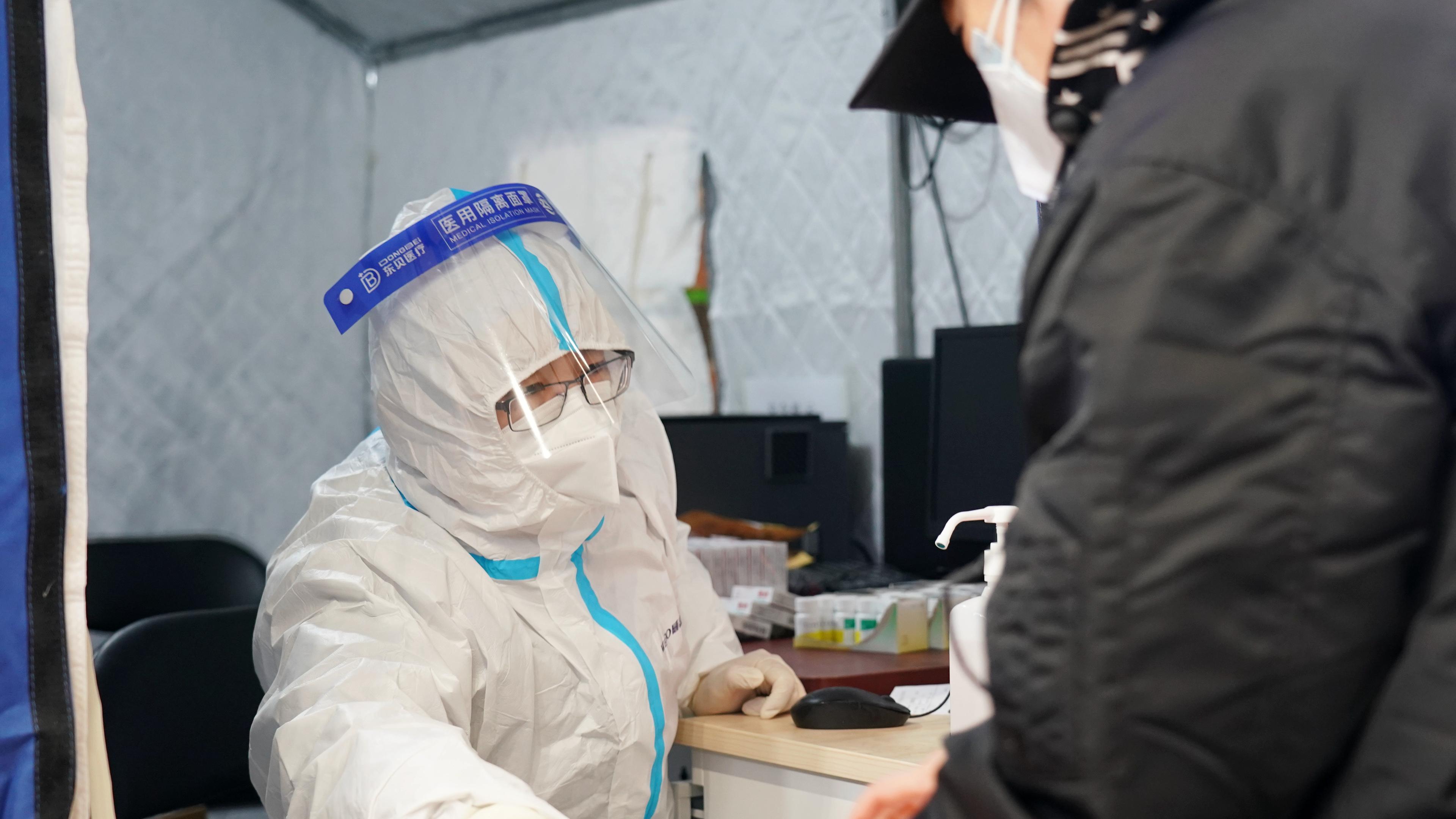 China, Peking: Ein Mitarbeiter einer behilfsmäßigen Fieberklinik in einer Turnhalle gibt Medizing an einen Fieberkranken aus.
