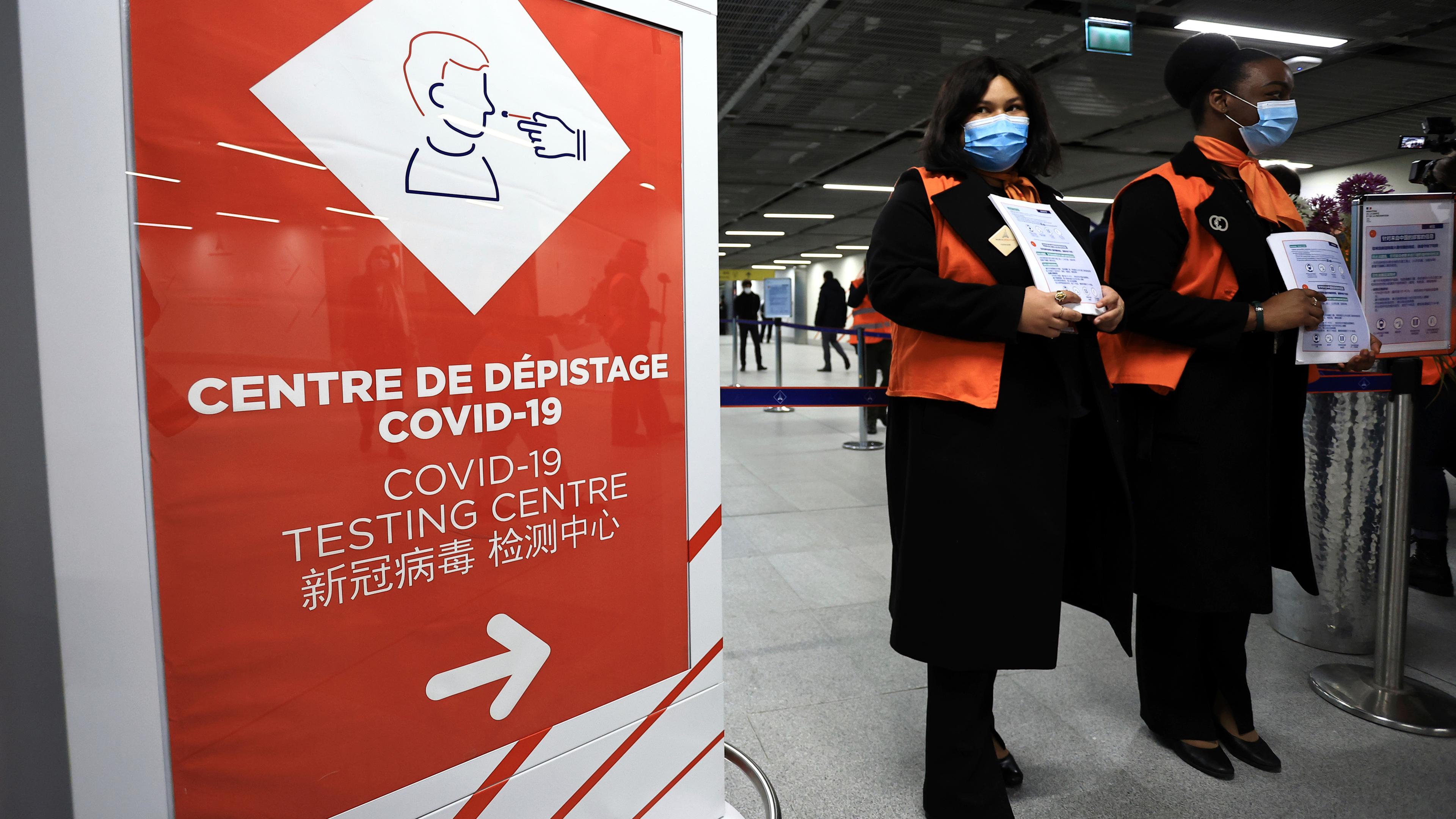 Zwei Flughafenmitarbeiterinnen warten auf Passagiere aus China vor einem Coronavirus-Testbereich auf dem Flughafen Roissy Charles de Gaulle.
