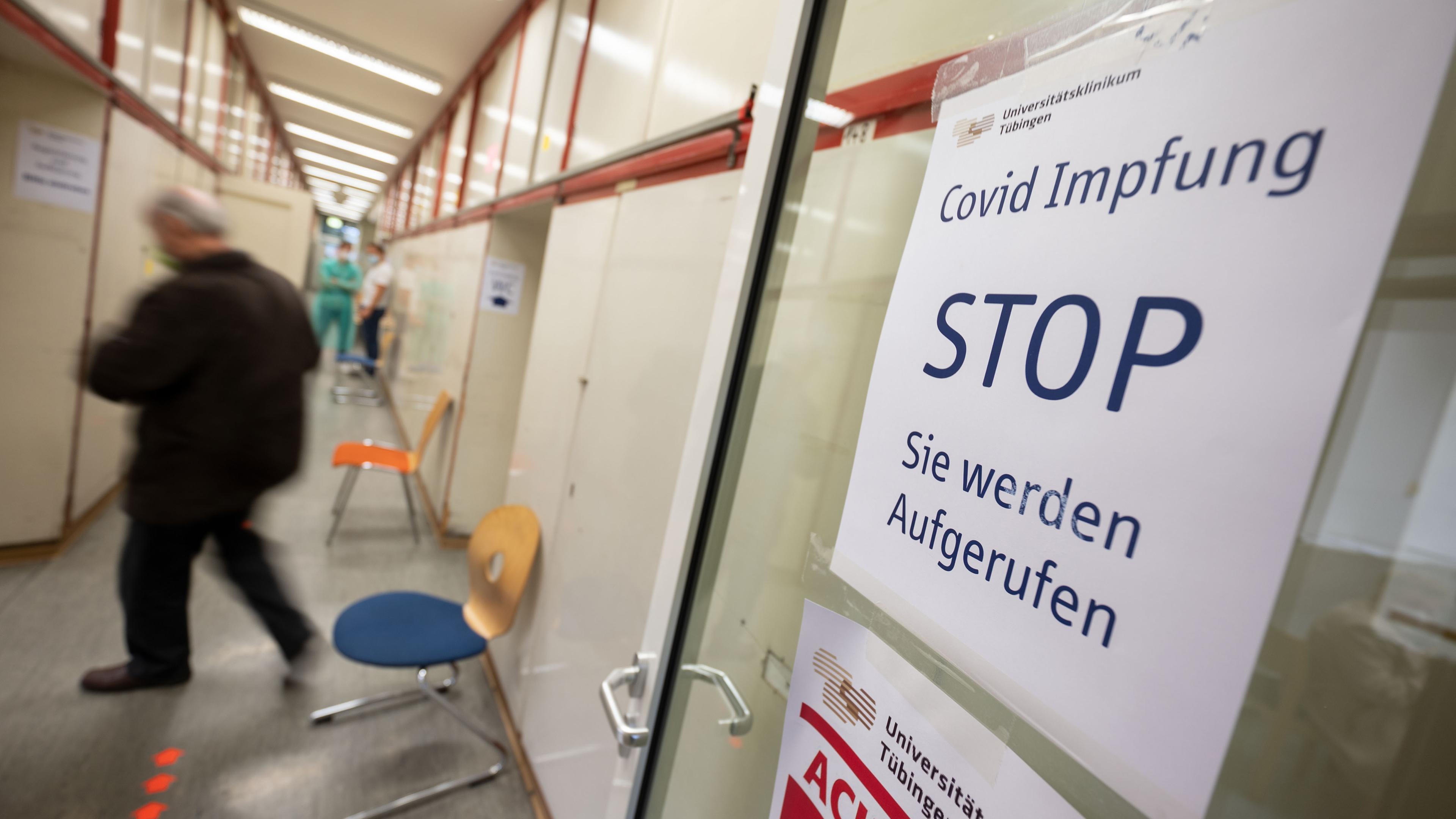 Ein Schild mit der Aufschrift "Covid Impfung Stop Sie werden aufgerufen" hängt an einer Tür.