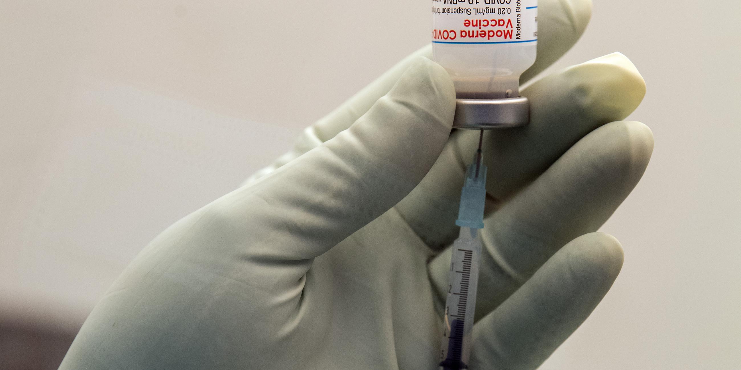 Eine Klinikmitarbeiterin zieht eine Spritze mit Impfstoff gegen Corona auf.