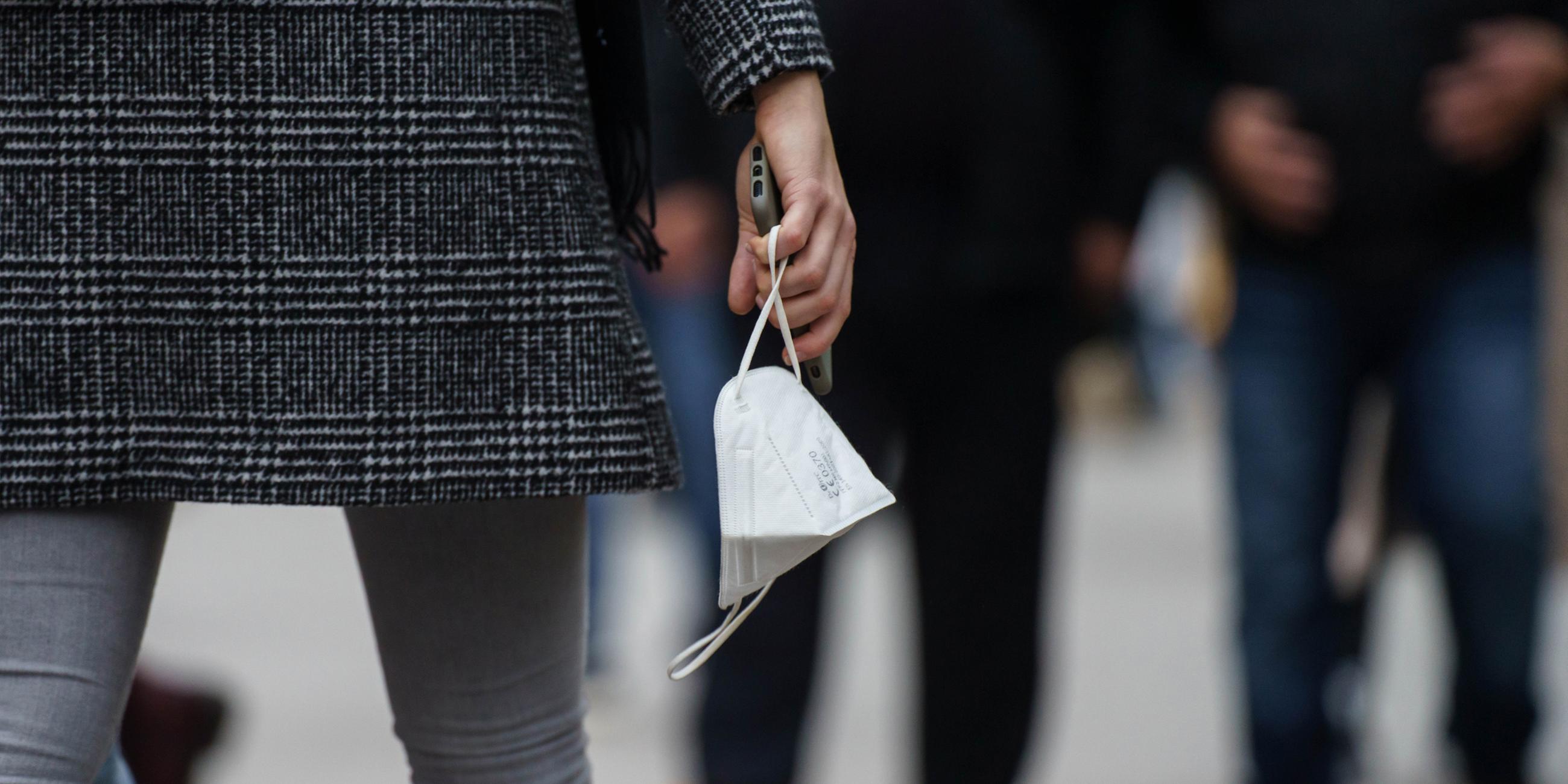 Eine Frau trägt am Nachmittag auf der Frankfurter Einkaufsmeile Zeil eine FFP-2-Maske in der Hand. 