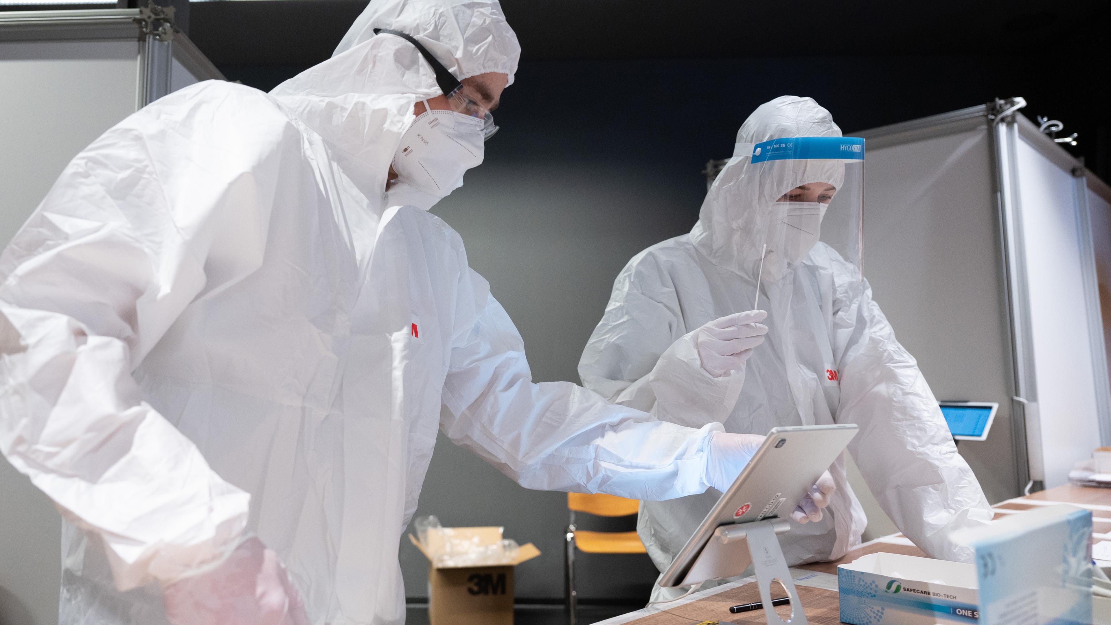 Mitarbeiter in Schutzanzügen sortieren Schnelltests in einem Corona-Testzentrum.