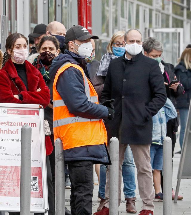 Wartende mit Masken vor einem Corona-Testzentrum in Köln
