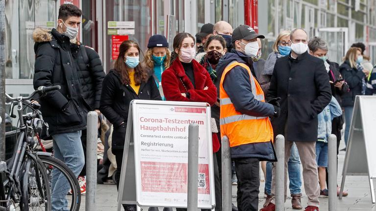 Wartende mit Masken vor einem Corona-Testzentrum in Köln