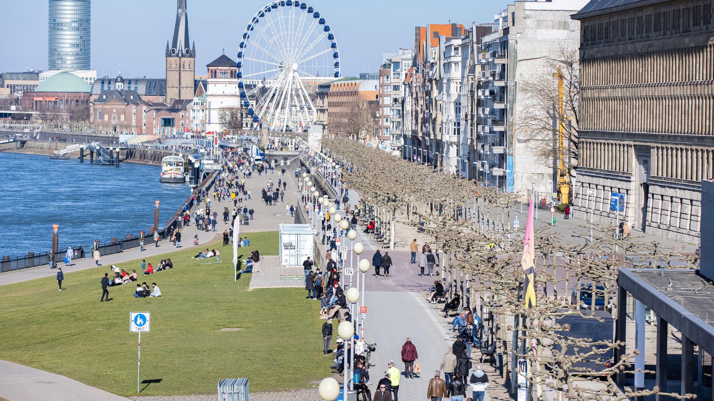Düsseldorf: Menschen gehen am Sonntag bei Sonnenschein am Rheinufer spazieren.
