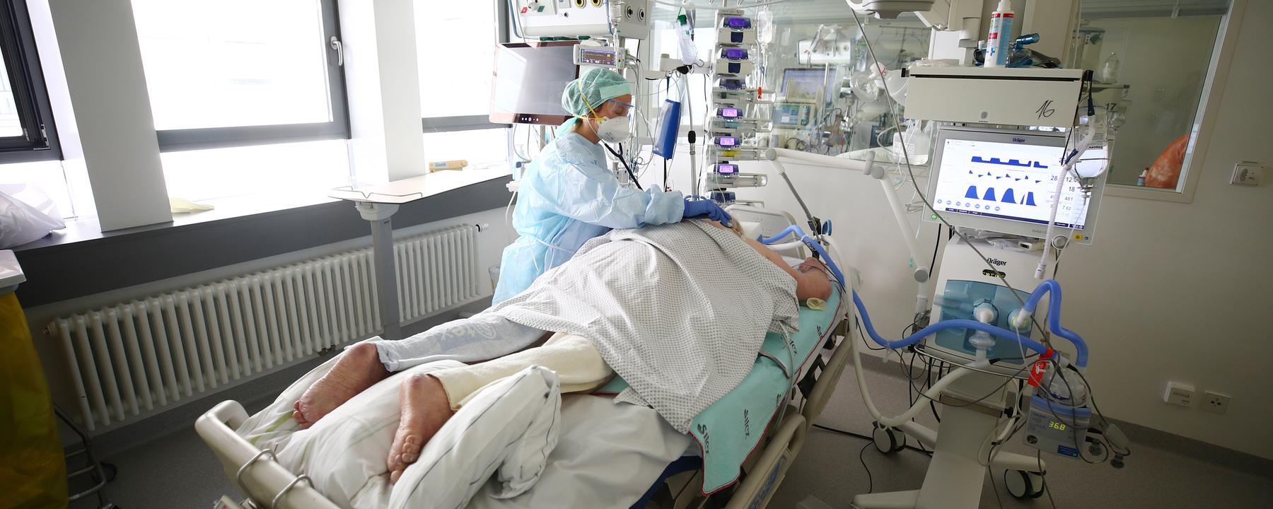 Pflegerin kümmert sich um einen Patienten auf der Covid-19 Intensivstation