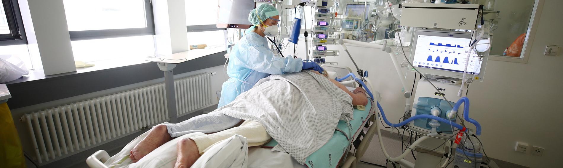 Pflegerin kümmert sich um einen Patienten auf der Covid-19 Intensivstation
