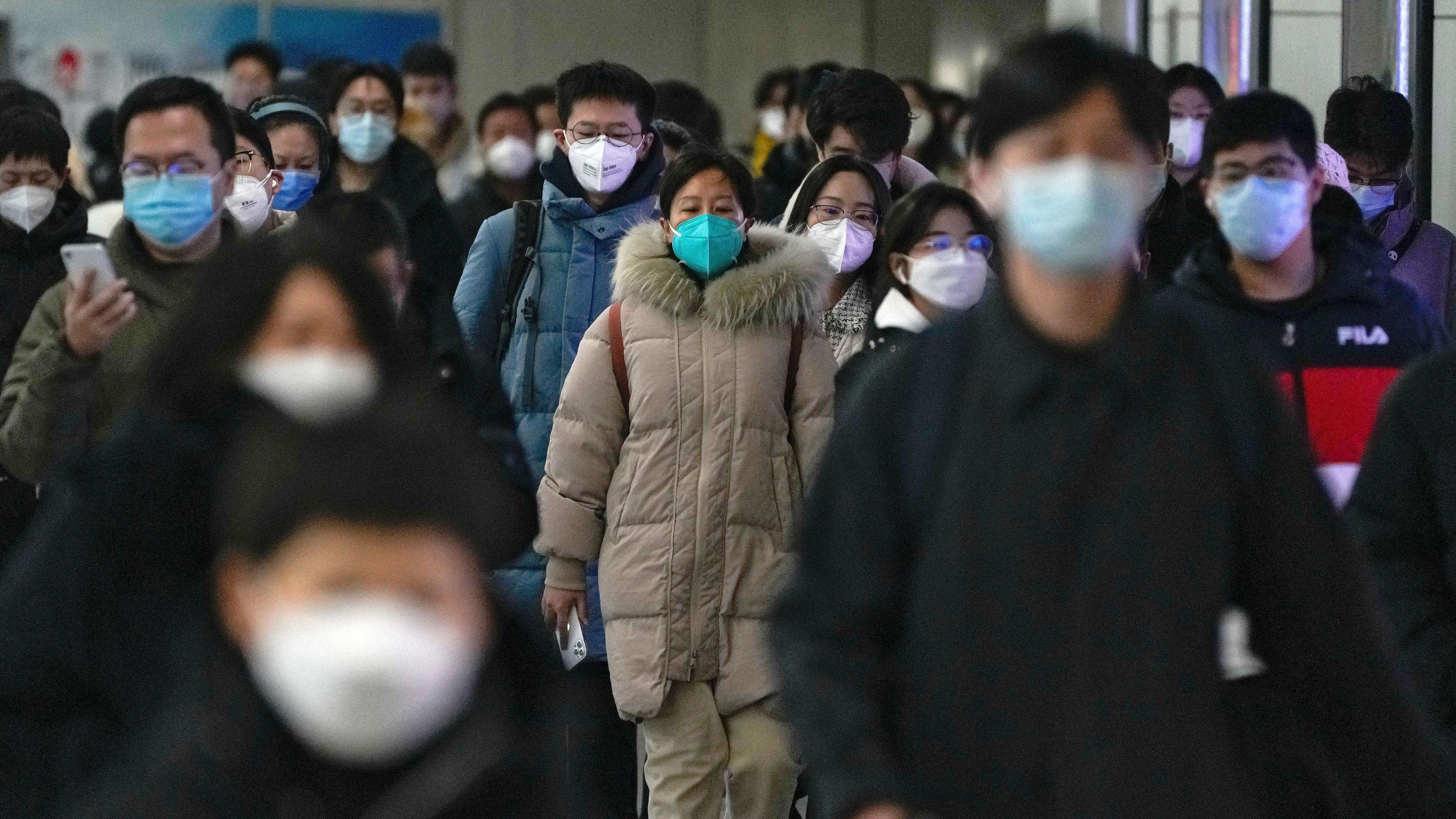 Pendler mit Schutzmasken gehen auf dem Weg zur Arbeit in Peking, aufgenommen am 20.12.2022