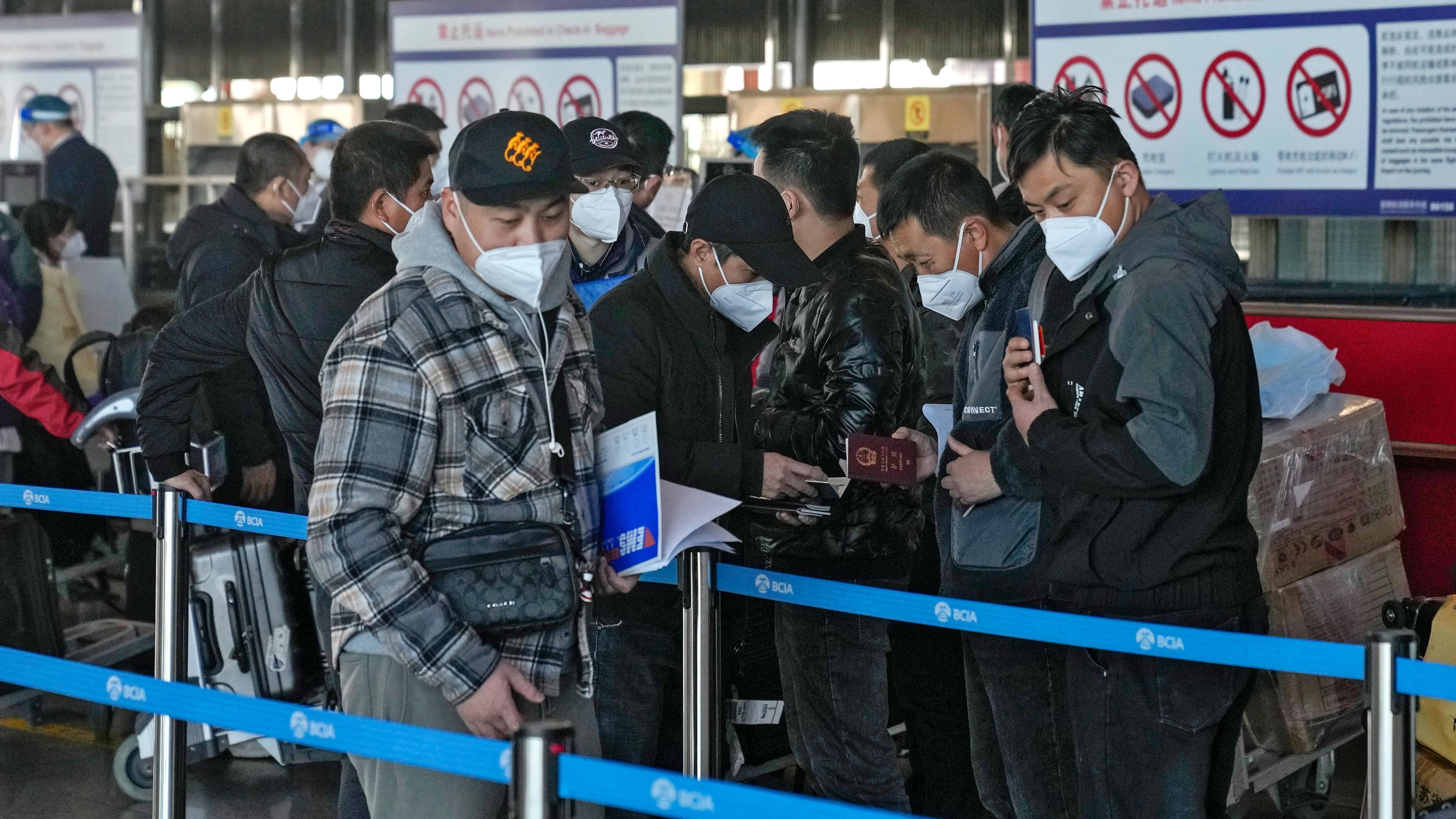 Reisende stehen am Check-in-Schalter für internationale Flüge auf dem Flughafen in Peking an, aufgenommen am 29.12.2022