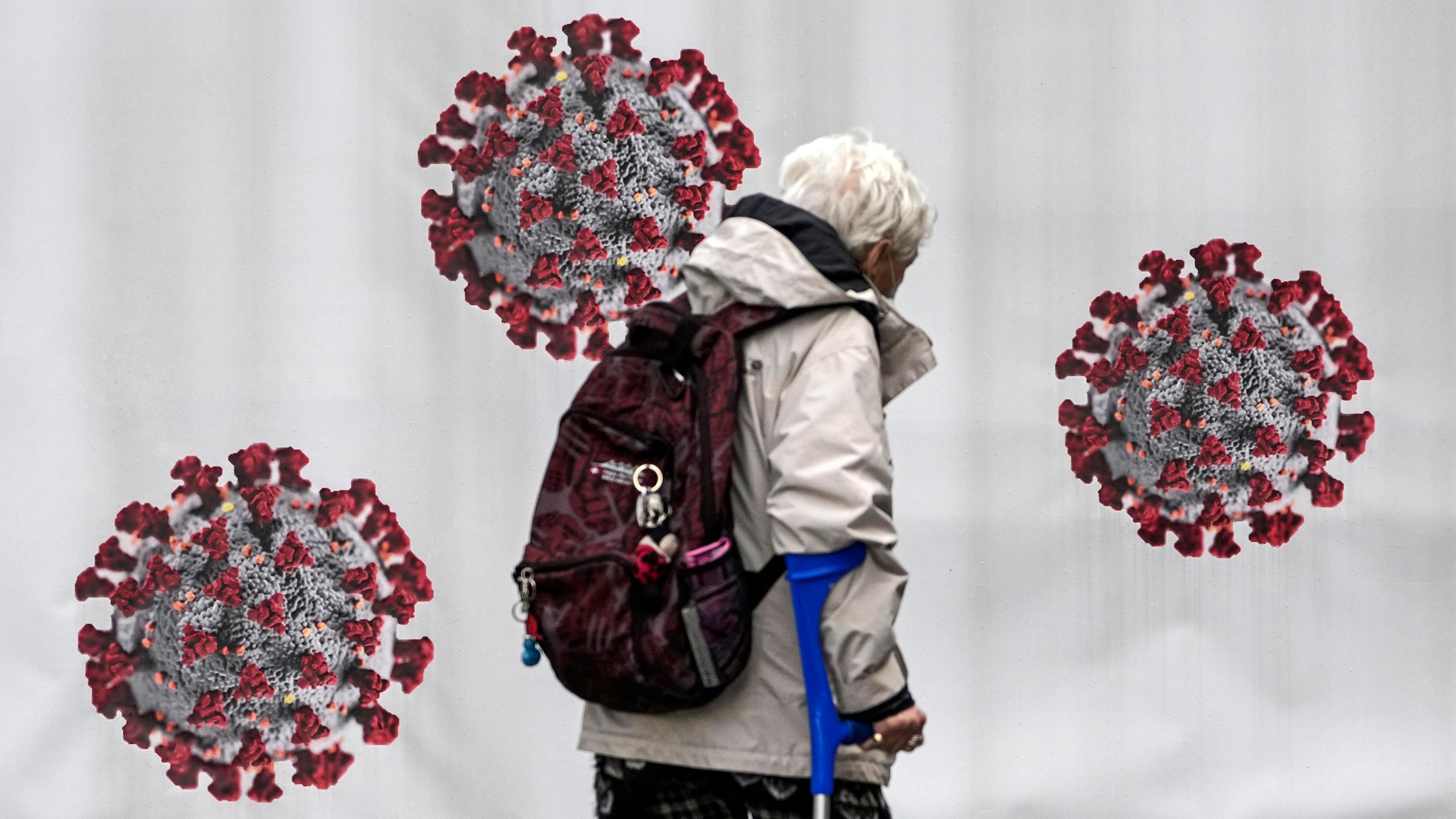 Eine ältere Frau läuft an einem Testcontainer mit Coronavirus-Aufklebern vorbei.