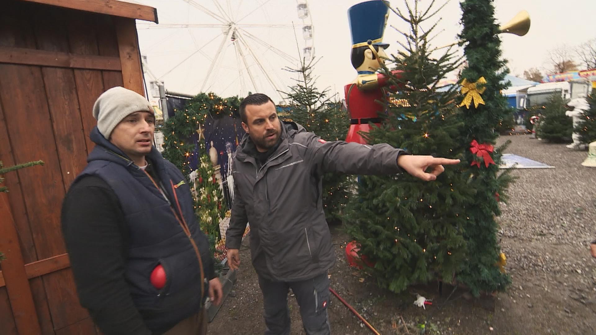 Platzmeister Sebastian Küchenmeister redet auf dem Weihnachtsmarkt mit einem Mann