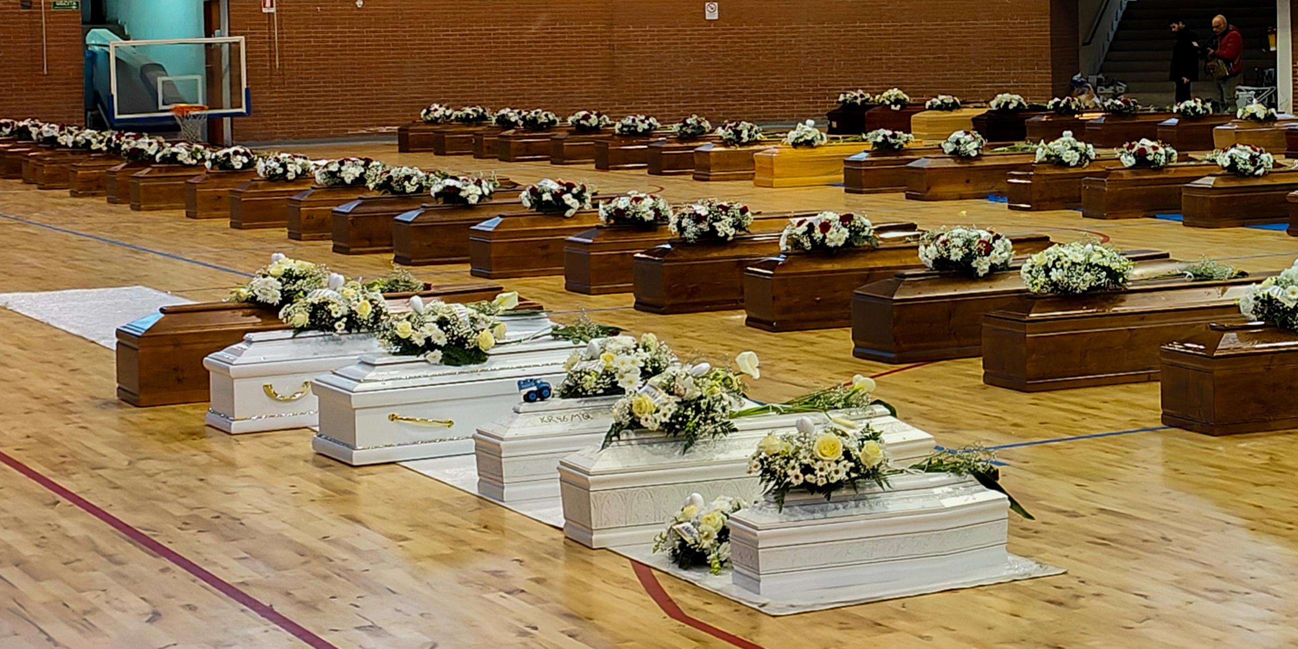 Die Särge der Opfer des Bootsunglücks stehen mit Blumen bedeckt in einer Sporthalle in Crotone.