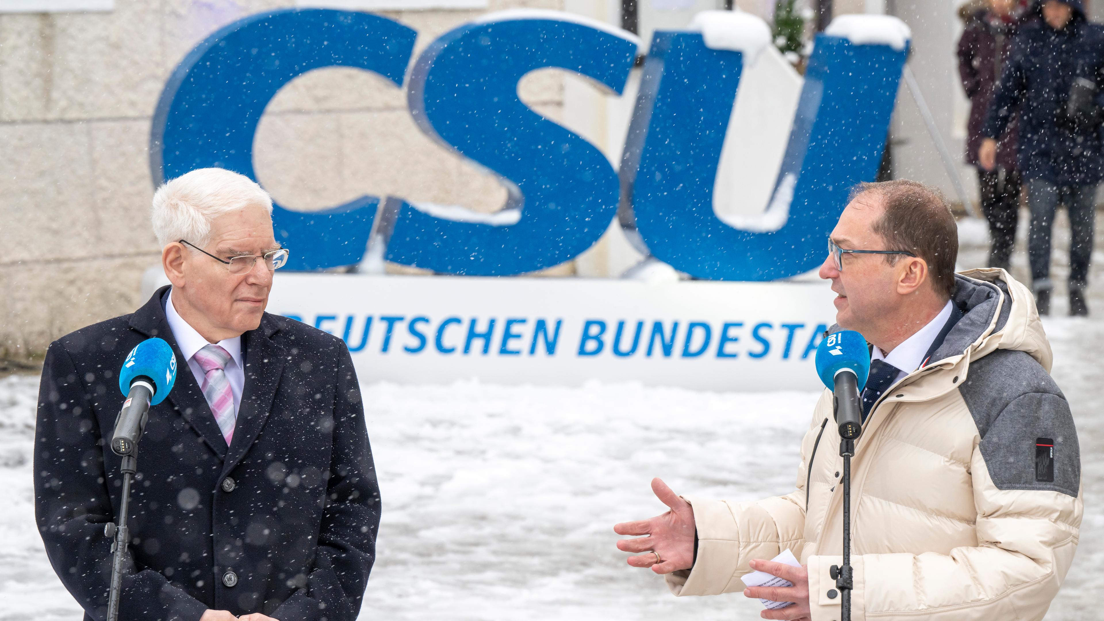 Josef Schuster und Alexander Dobrint hinter Mikrofonen im Schnee