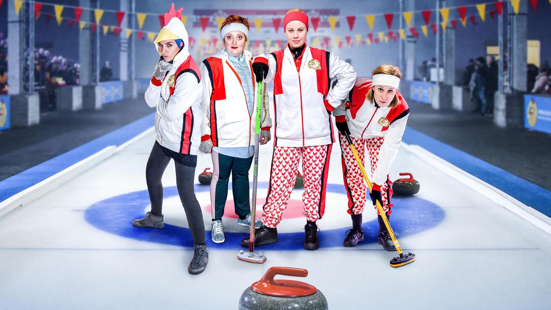 4 Frauen in Sportkleidung posieren auf einer Curlingbahn für die Kamera