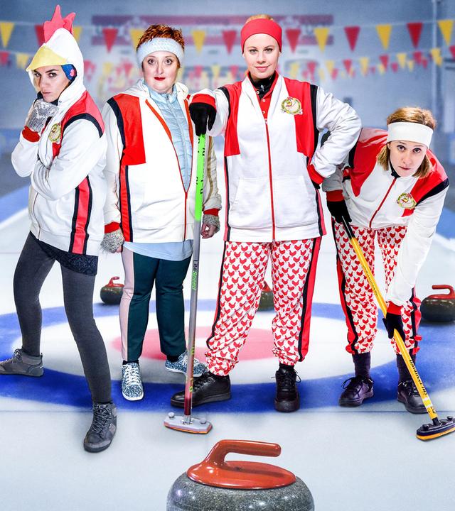4 Frauen in Sportkleidung posieren auf einer Curlingbahn für die Kamera