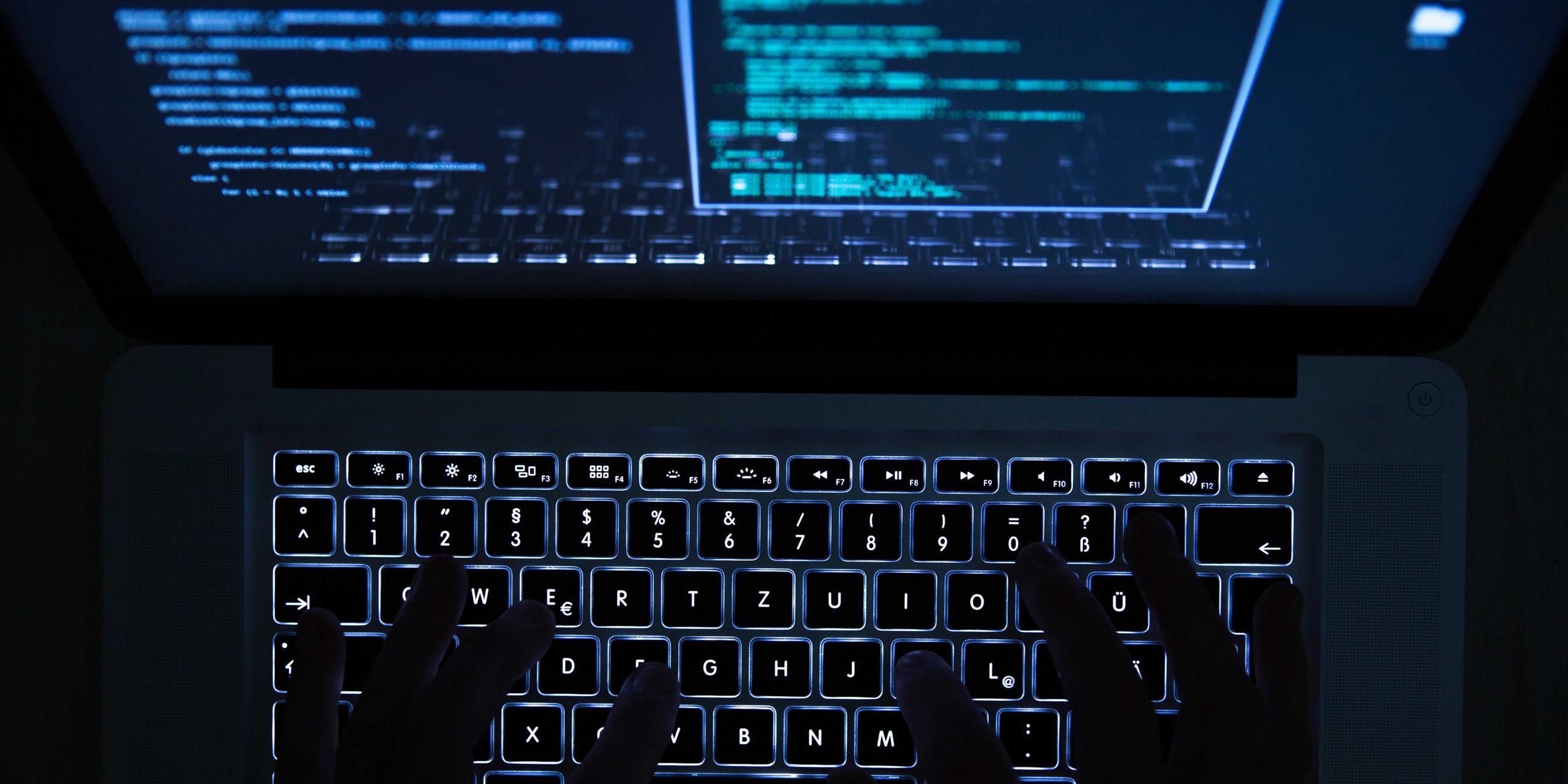 Ein mann bedient eine beleuchtete tastatur eines laptops. 