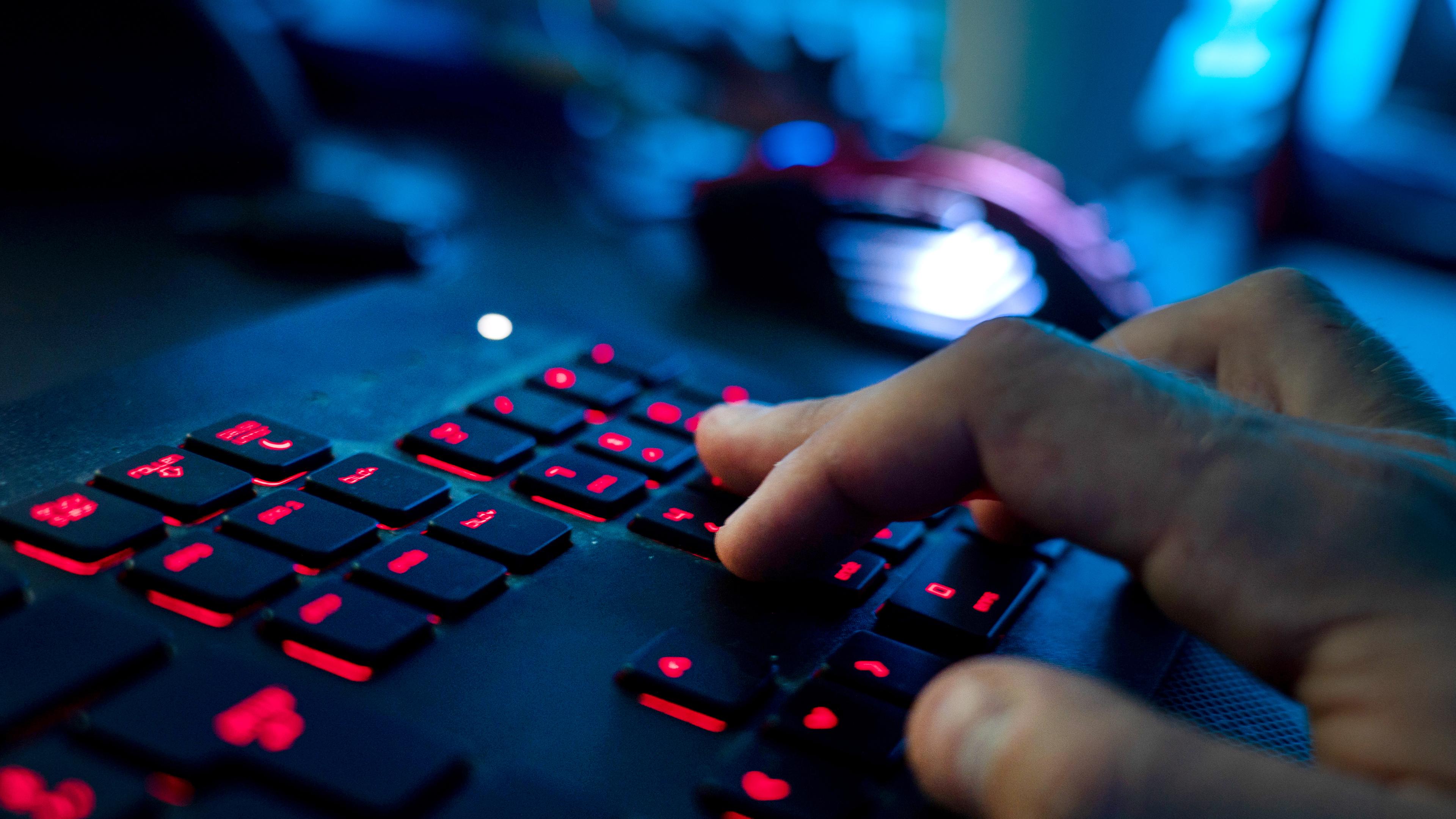 Symbolbild:  Ein Mann sitzt am Rechner und tippt auf einer Tastatur. 