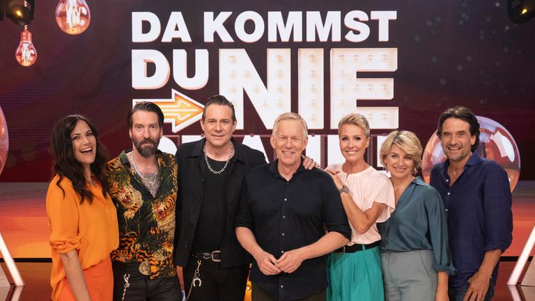 "Da kommst Du nie drauf!": Gruppenfoto vor Sendungslogo: Bettina Zimmermann, Alec Völkel und Sascha Vollmer (The BossHoss), Johannes B. Kerner, Sonja Zietlow, Sabine Heinrich und Oliver Mommsen stehen nebeneinander und lächeln in die Kamera.
