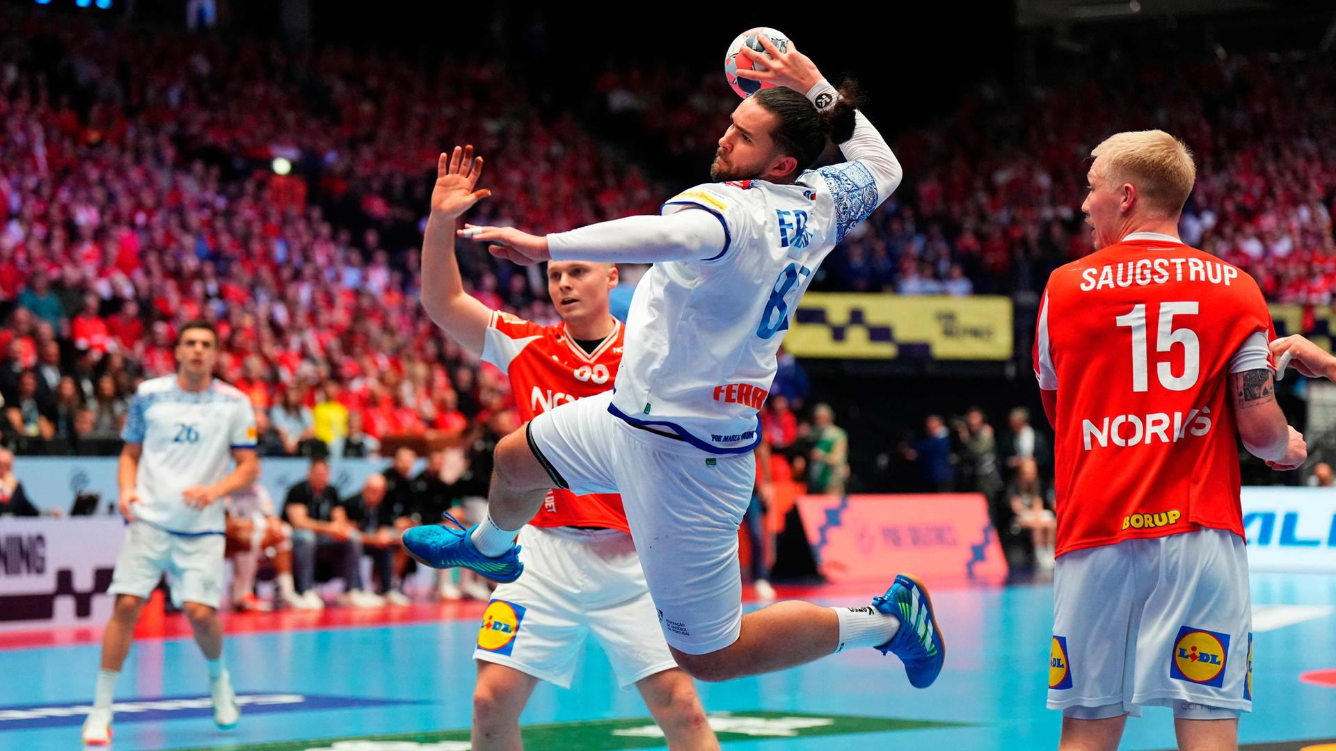 Mathias Gidsel beim Sprungwurf aus dem Rückraum. Leonel Fernandes und Victor Iturriza behindern ihn.