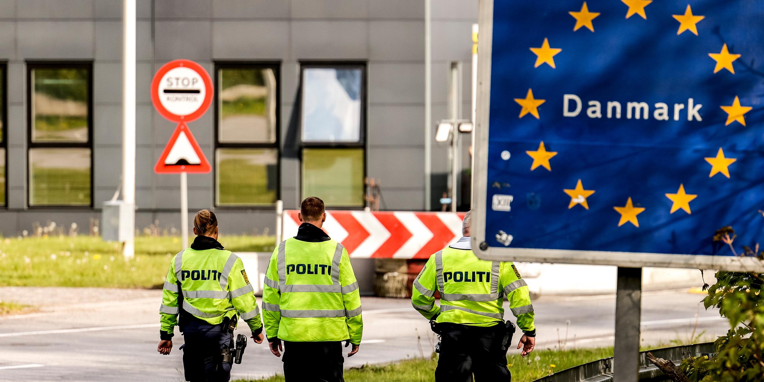 Dänische Polizisten laufen an der deutsch/dänischen Grenze auf einem Fußgängerweg.