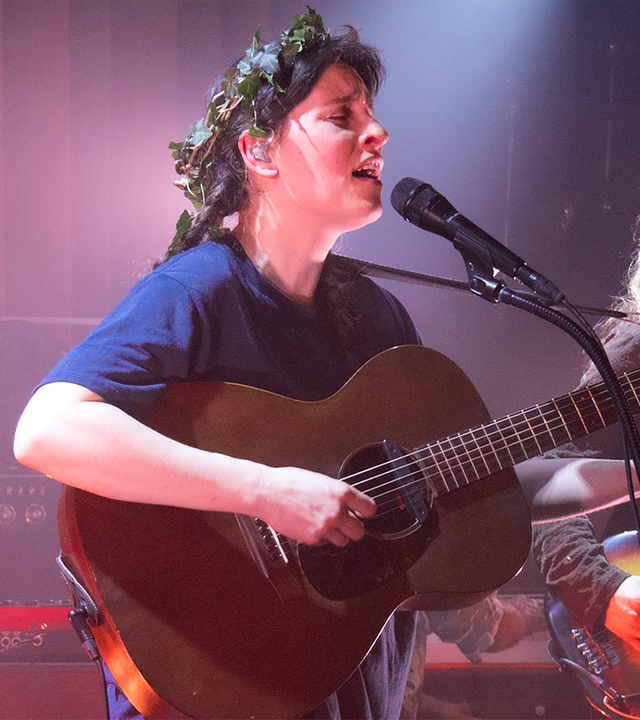 Frontfrau Janine Cathrein steht auf der Bühne mit Gitarre und singend.