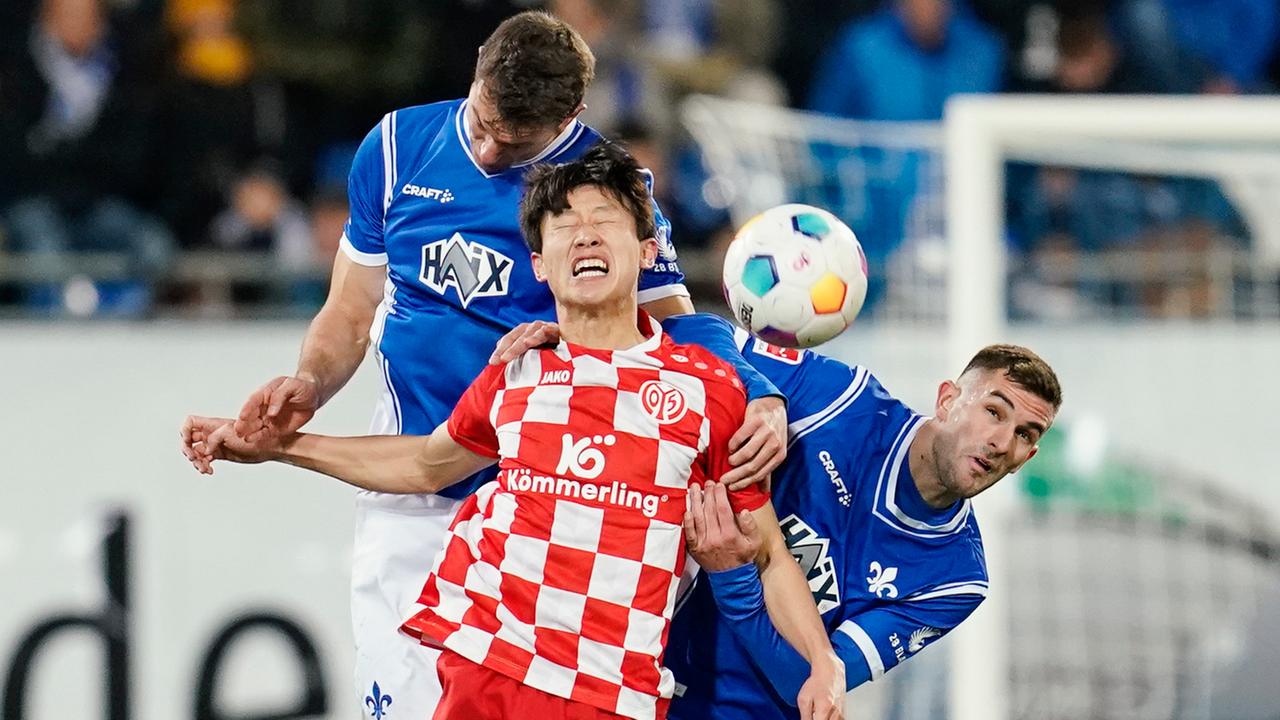 Darmstadts Christoph Zimmermann, Jae-Sung Lee von Mainz und Darmstadts Bartol Franjic kämpfen um den Ball.