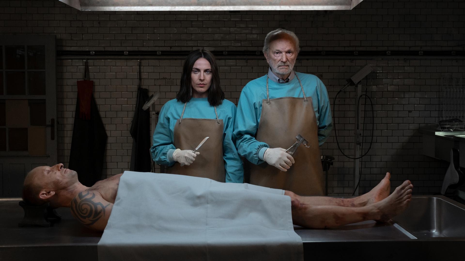 Emma und Peter stehen vor einer obduzierten Leiche