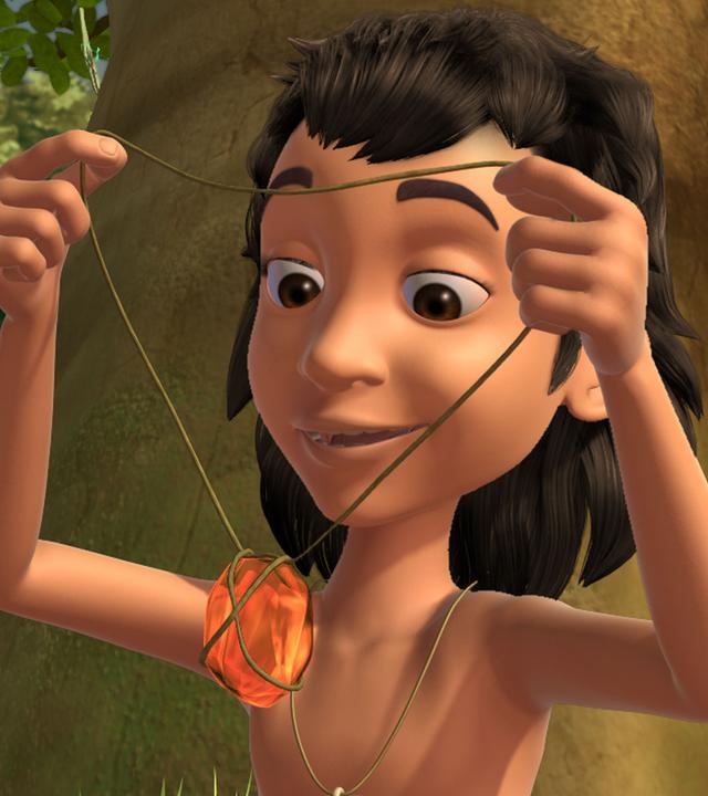 Mogli hält den Bernstein in den Händen.