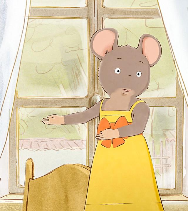 Celestine steht auf dem Esstisch und führt ihren Freundinnen ein gelbes Kleid mit orangener Schleife vor. 