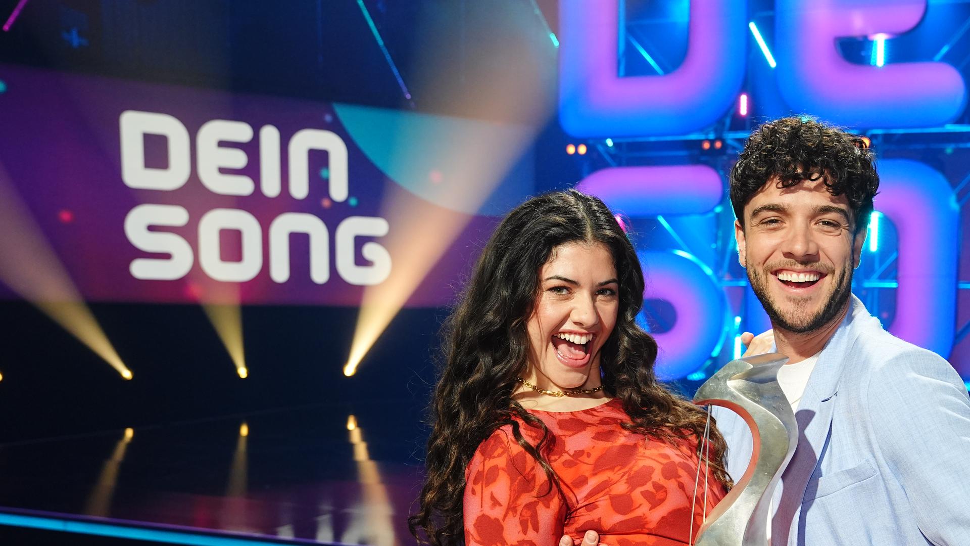Jeannie Naomie Wagner und Luca Hänni stehen auf der "Dein Song" Bühne und halten den "Dein Song" Pokal in den Händen.